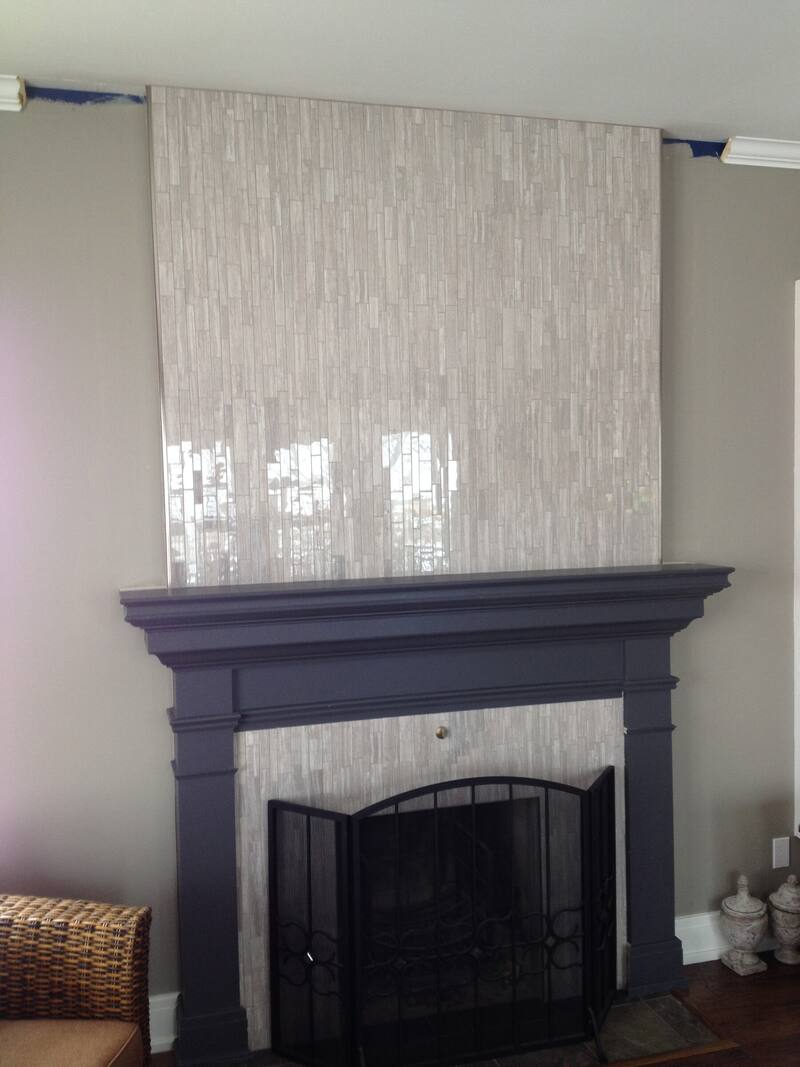 Glossy vertical tile panel above a painted fireplace mantel with a tile surround