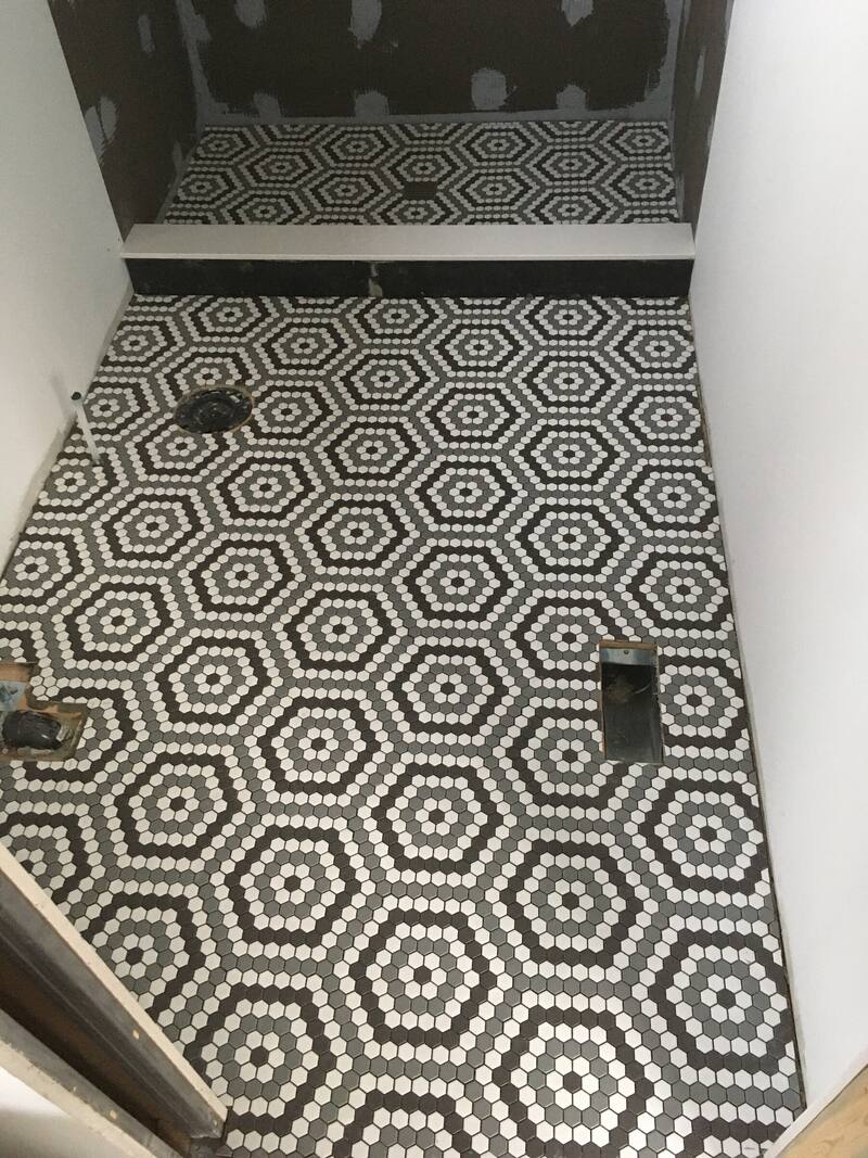 Black and white hexagon mosaic bathroom floor with a linear drain
