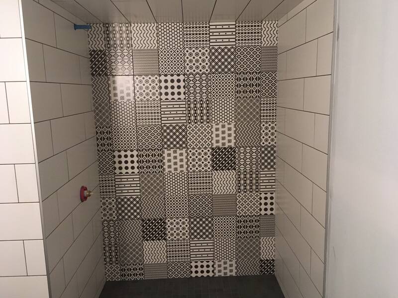 Shower with a black and white patterned tile feature wall framed by white subway tile