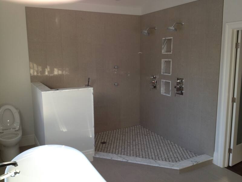 Large corner shower with grey wall tile, three recessed niches and a mosaic floor